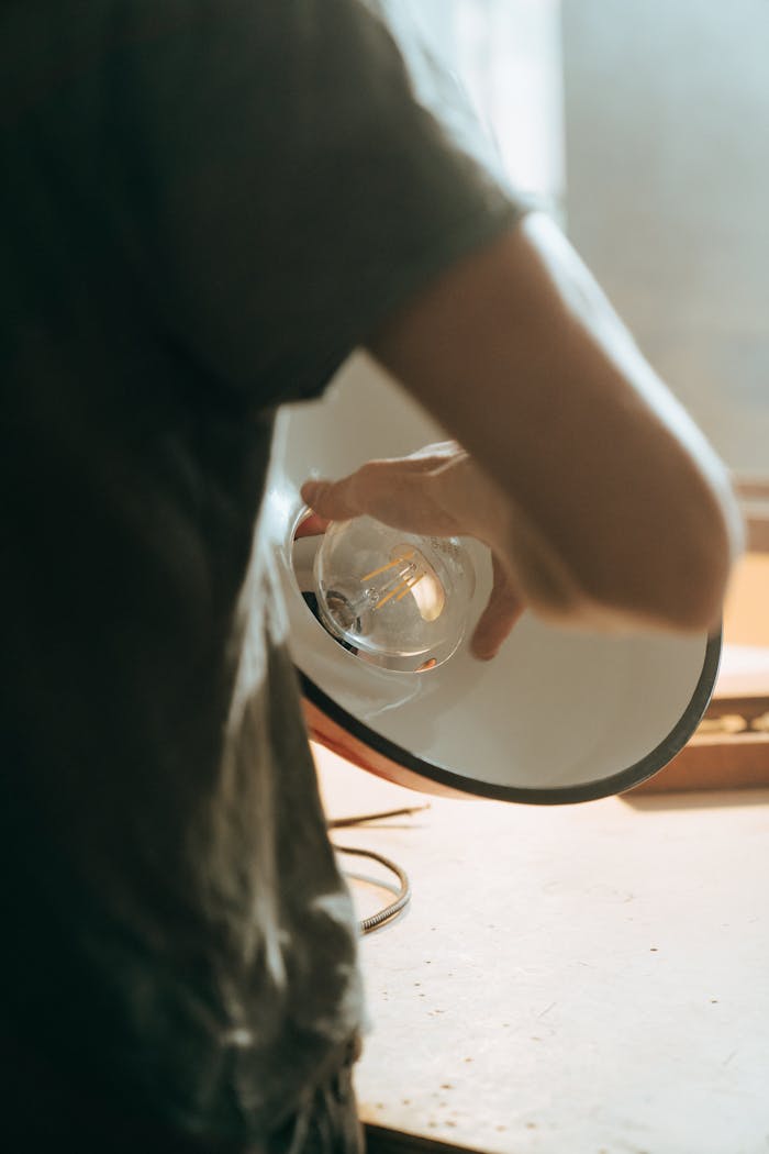 digital Person adjusting a vintage lightbulb inside a repair workshop setting.